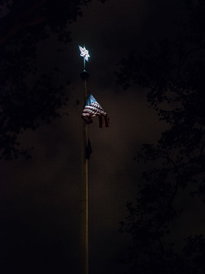 faintly lit flag on flagpole at night