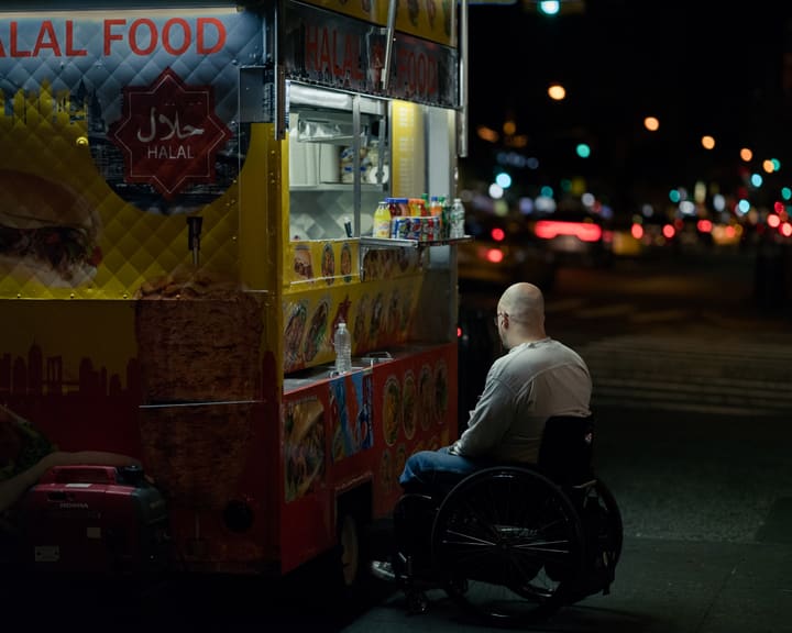man in wheelchair at food truck, night