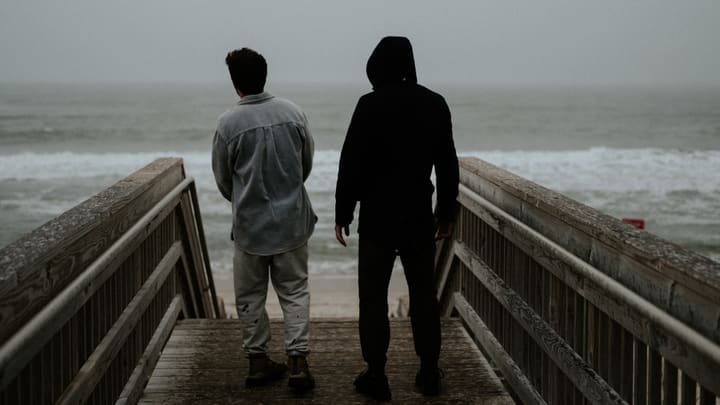 two figures on pier over ocean