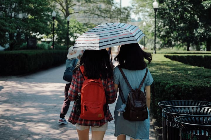 two girls under umbrella in park