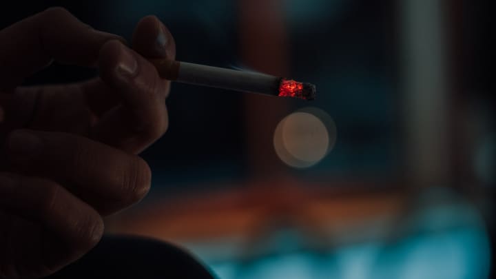hand holding lit cigarette