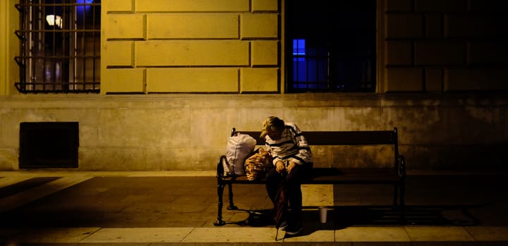 person sleeping on bench at night