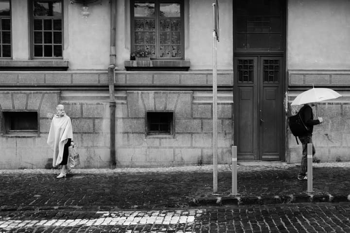 woman walking past man with umbrella