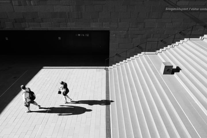two people running past geometric stairs